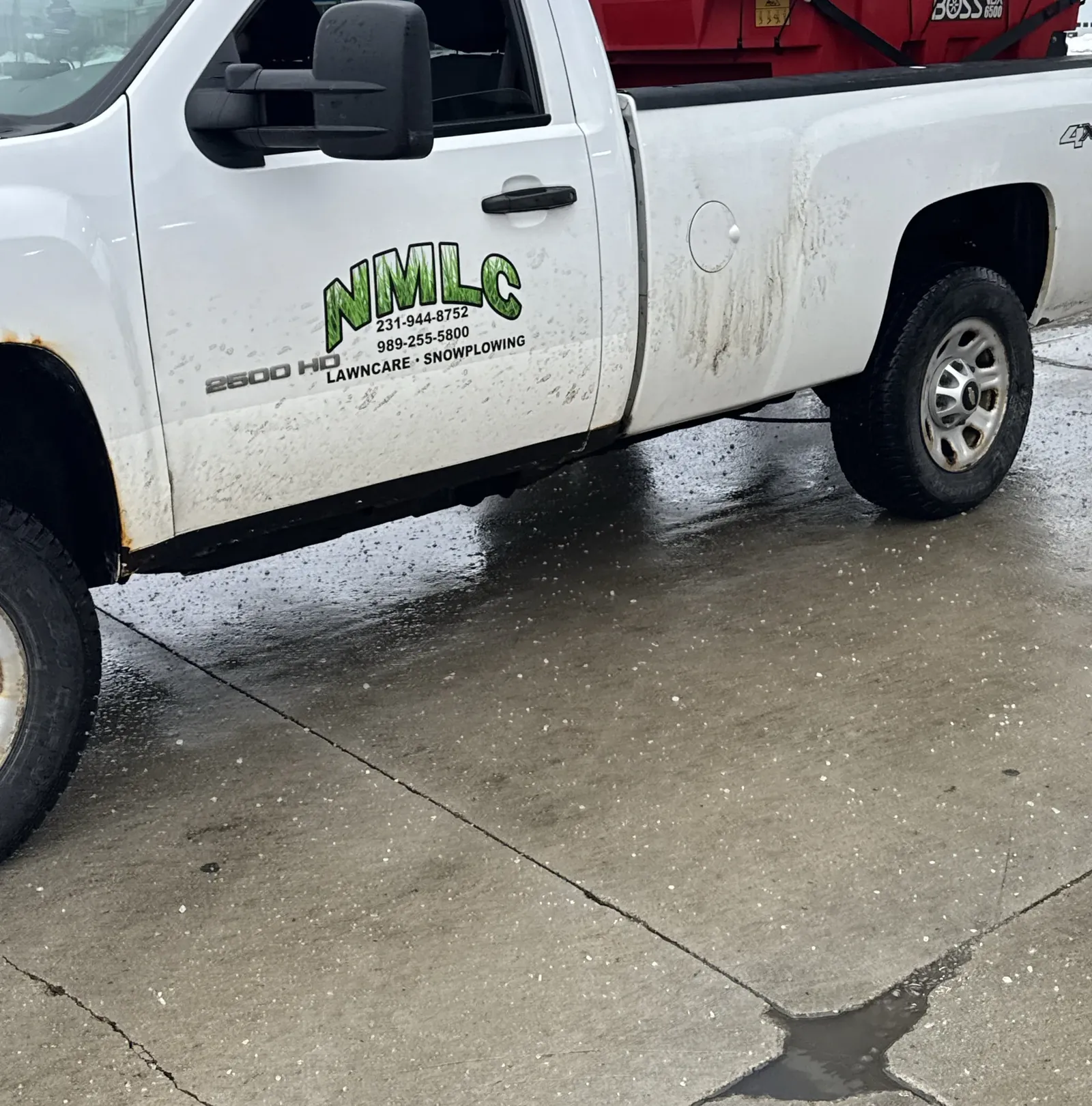 White NMLC pickup with a red BOSS salt spreader in the bed